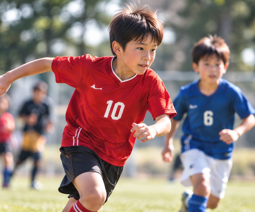 サッカーの試合でボールを追う少年たち